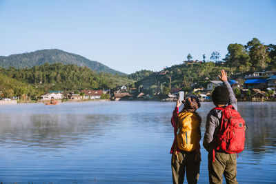 Rear view of people standing on mountain against sky