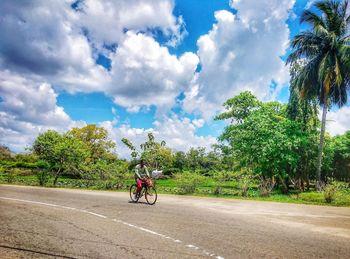 Man riding bicycle on road against sky