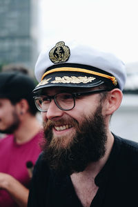 Smiling bearded man wearing eyeglasses and cap in city