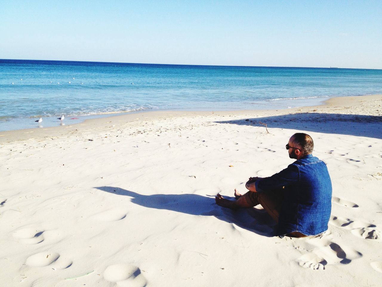 beach, sea, sand, shore, horizon over water, lifestyles, leisure activity, water, person, full length, clear sky, casual clothing, childhood, vacations, young adult, sitting, relaxation, summer