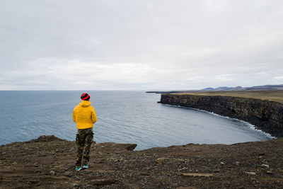 Man in yellow jacket overlooking the cliff in iceland