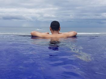 Rear view of shirtless in sea against sky