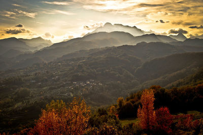 Scenic view of valley and mountains against sky during sunset