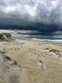 Scenic view of beach against cloudy sky