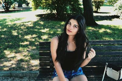 Portrait of a smiling young woman sitting against trees