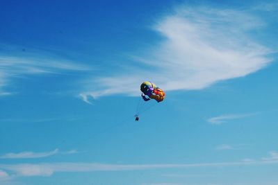 Low angle view of person paragliding against blue sky