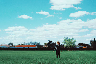 Man standing on grass against sky