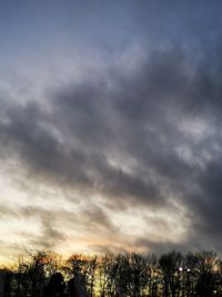 Low angle view of silhouette trees against dramatic sky