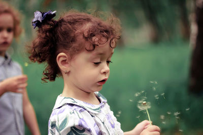 Close-up of cute girl playing with dandelion at park