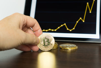 Close-up of hand holding coins on table