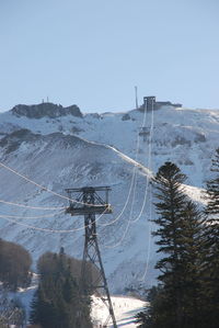 Ski lift over snowcapped mountains against clear sky