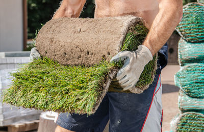 Midsection of man carrying gardening equipment