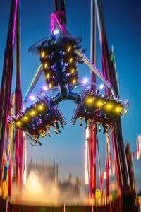 Low angle view of illuminated amusement park ride against sky at night