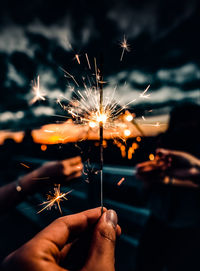 Selective focus of several hands holding fireworks at dusk. creative background template.