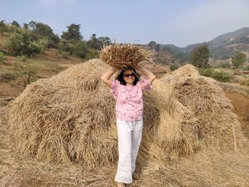 Man standing on hay bales on field