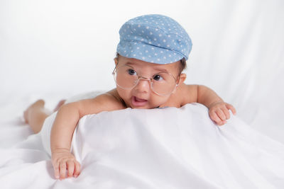 Close-up of cute baby boy lying on white backdrop