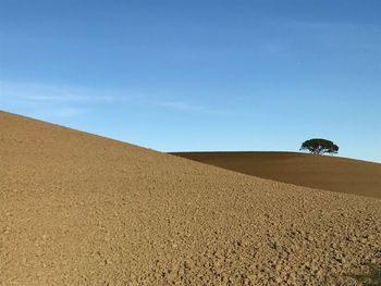 Scenic view of sand dunes against blue sky