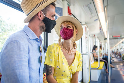 Smiling couple wearing mask sitting in bus