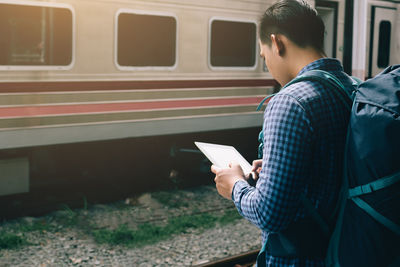 Man using digital tablet at railroad station