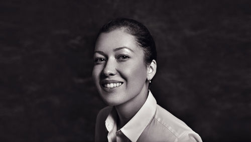 Close-up portrait of woman smiling against wall