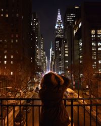 Rear view of man standing in city at night