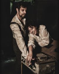 Young man and woman with arms raised at night