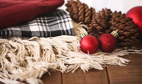 Close-up of baubles and pine cones by blankets on table