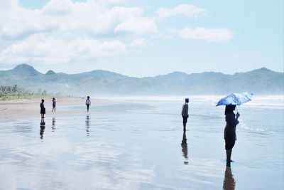 People at beach against sky