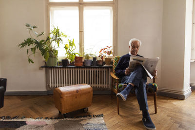 Senior man reading newspaper at home