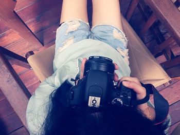 High angle view of woman photographing with camera while sitting on chair