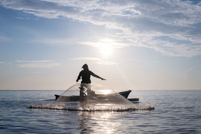 Rear view of man in boat on sea during sunset