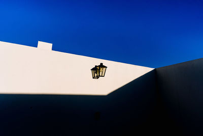 Low angle view of a lamp on building against clear blue sky