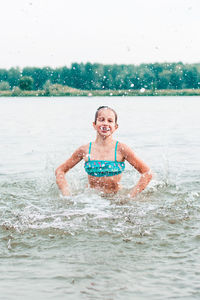 Cheerful girl makes splashes in the river. local tourism. summer vacation
