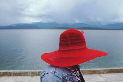 Woman in red hat against calm lake