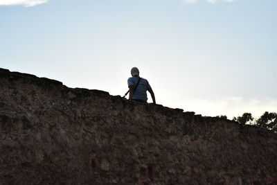 Rear view of man standing on mountain against sky