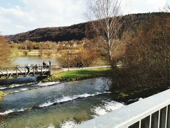 People by river against sky