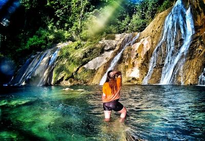 Full length of young woman standing on rock by river