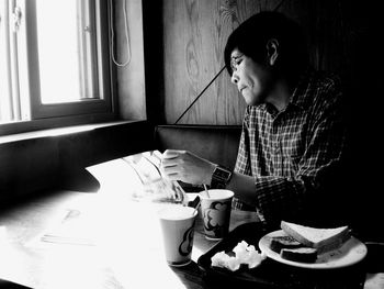 Man holding camera while sitting in kitchen