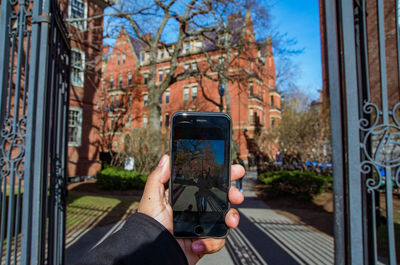 Cropped hand photographing female friend in campus