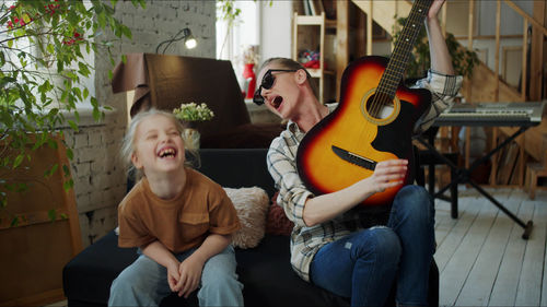 Mother and daughter playing guitar at home