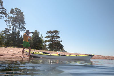 Man standing in boat against sky