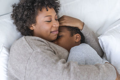 Son sleeping in mother's arms at home