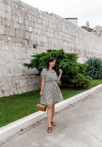 Full length of woman standing against wall