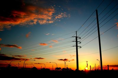 Low angle view of electricity pylon against cloudy sky