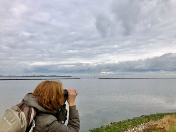 Rear view of woman photographing sea against sky