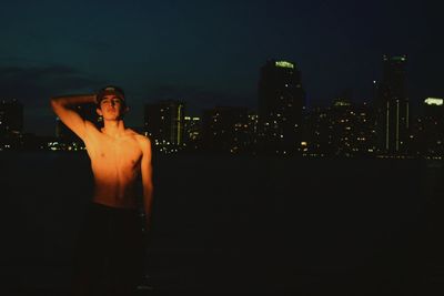 Man standing by illuminated building at night