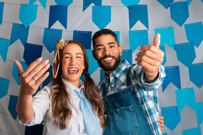 Portrait of smiling friends with arms raised