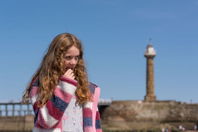 Portrait of young woman standing against clear sky