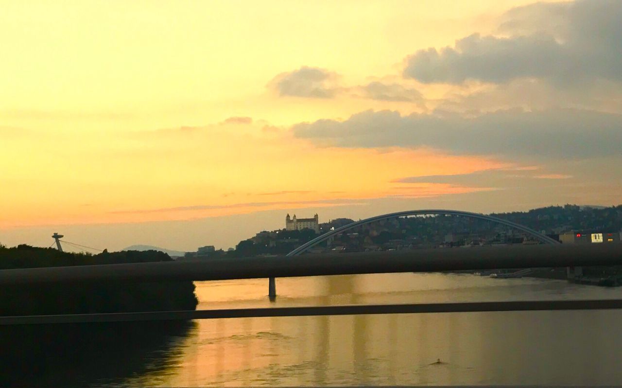 BRIDGE OVER RIVER IN CITY AGAINST SKY DURING SUNSET