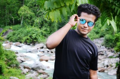 Portrait of young man against stream in forest